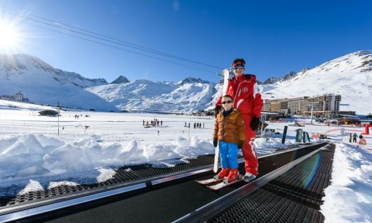 A little child is using the magic carpet to get back up the training area in Tignes.