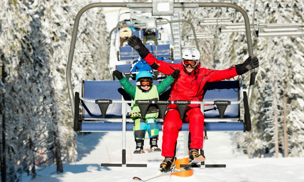 Ein kleines Kind und sein Skilehrer fahren mit dem Lift.