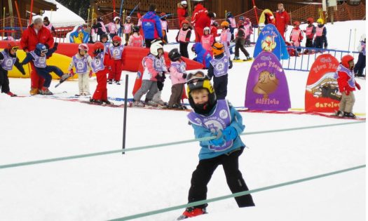 In einem bunten Übungsgelände haben Kinder Spaß beim Skifahren lernen