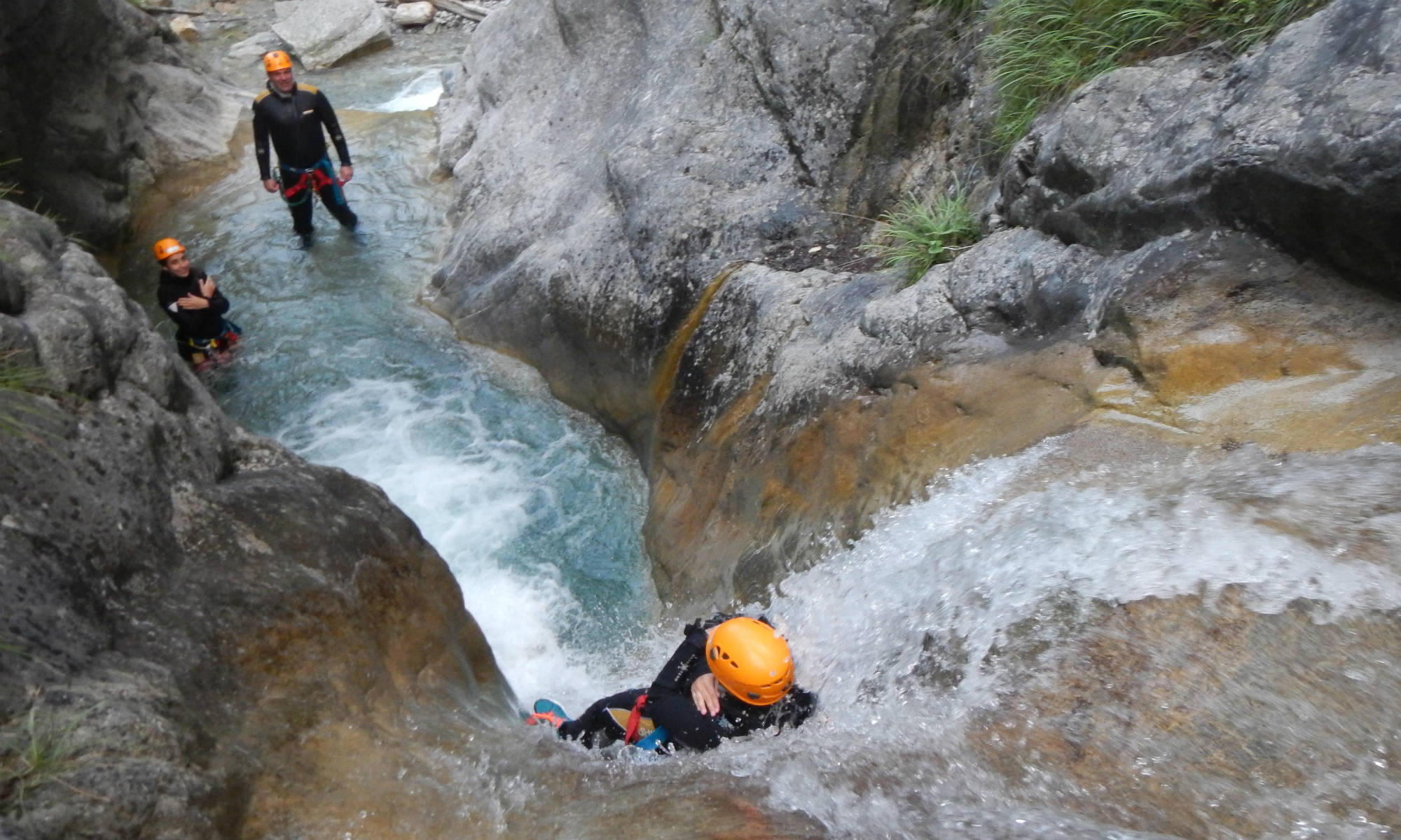 Eine geführte Gruppe rutscht beim Canyoning in Österreich an einer Felswand hinunter.