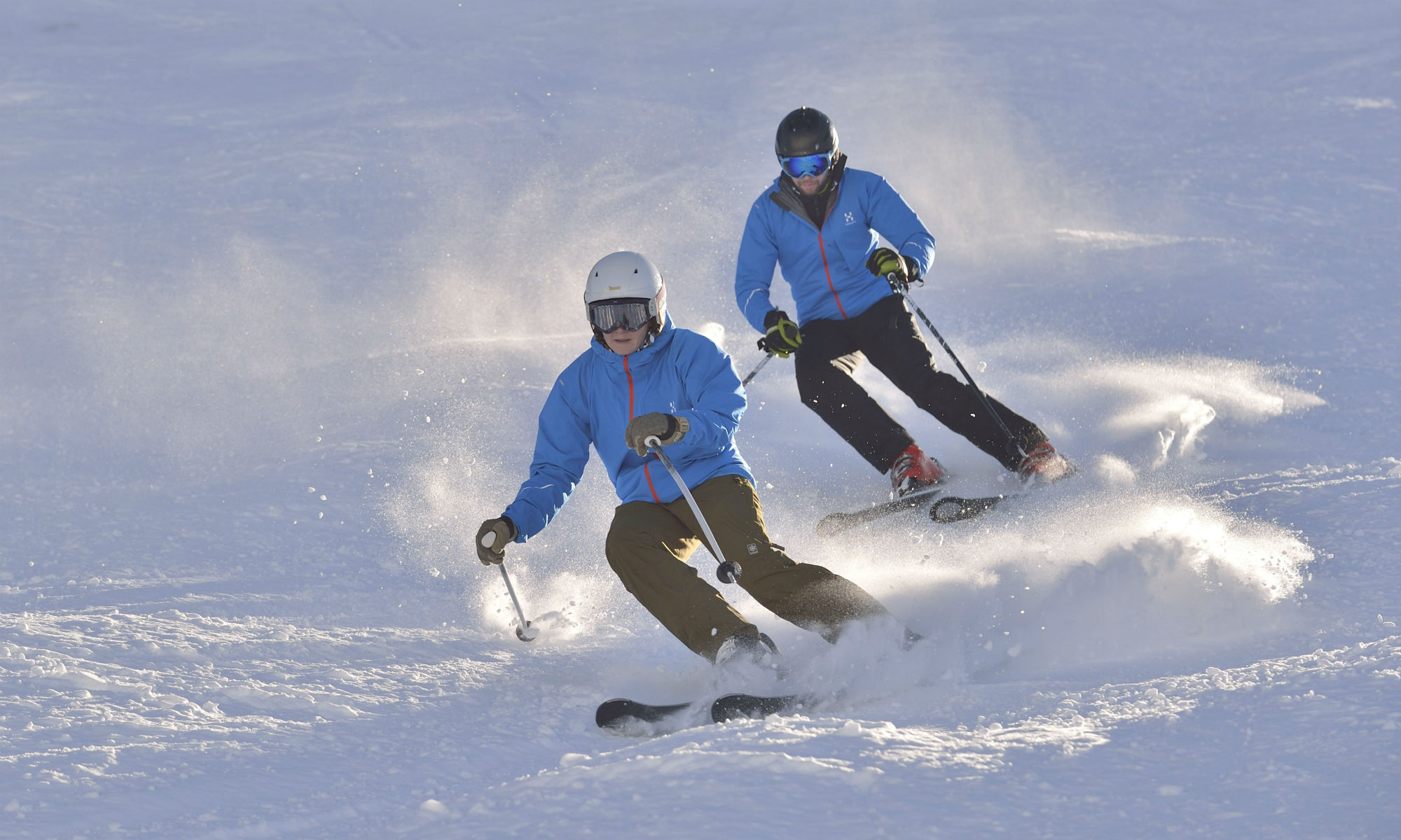 2 Skifahrer beim Üben der Skitechnik auf der sonnigen Piste.