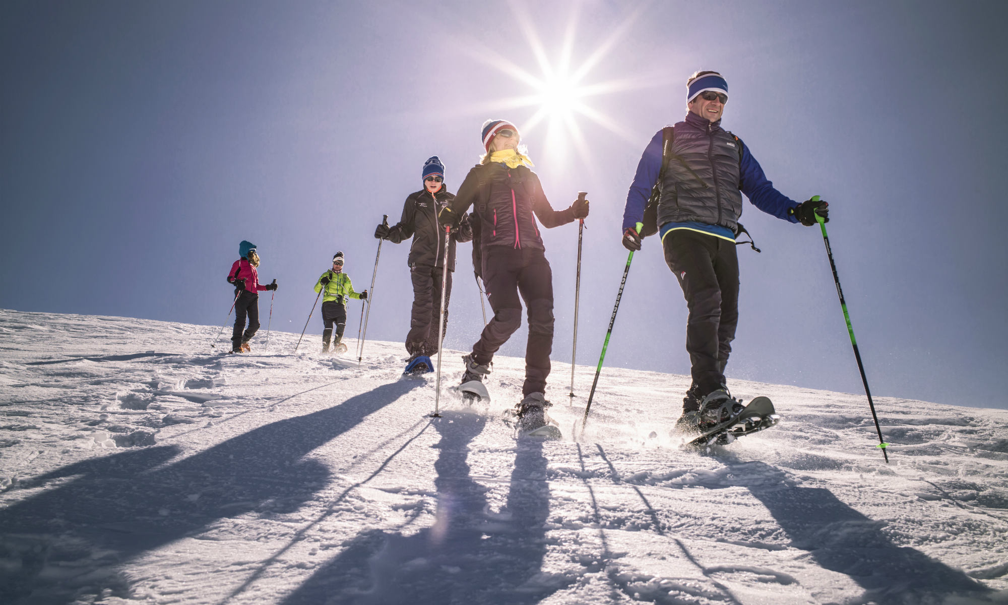 5 Personen bei einer Schneeschuhwanderung im Sonnenschein.
