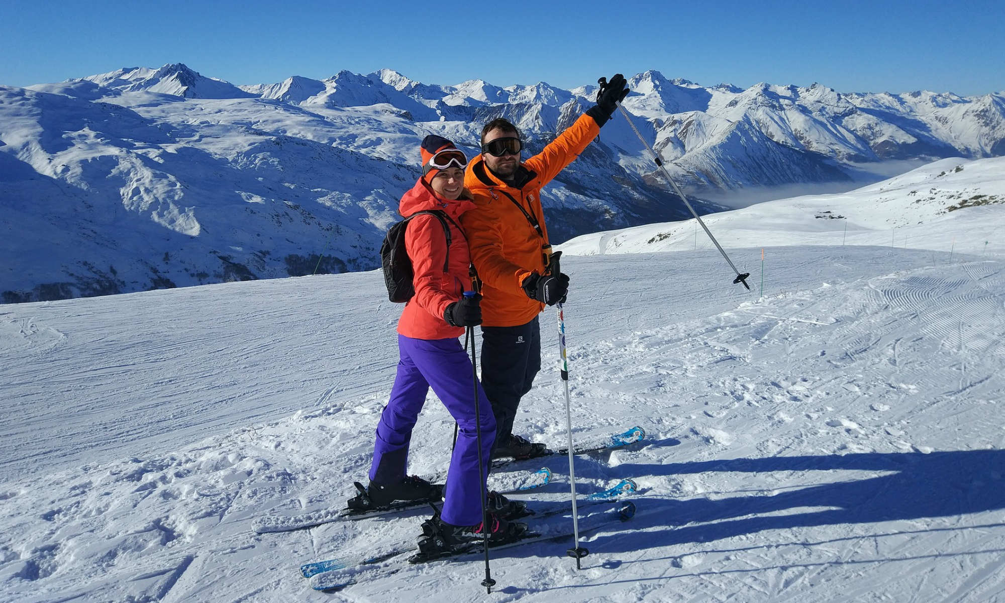 Deux skieurs souriants sur une piste ensoleillée.