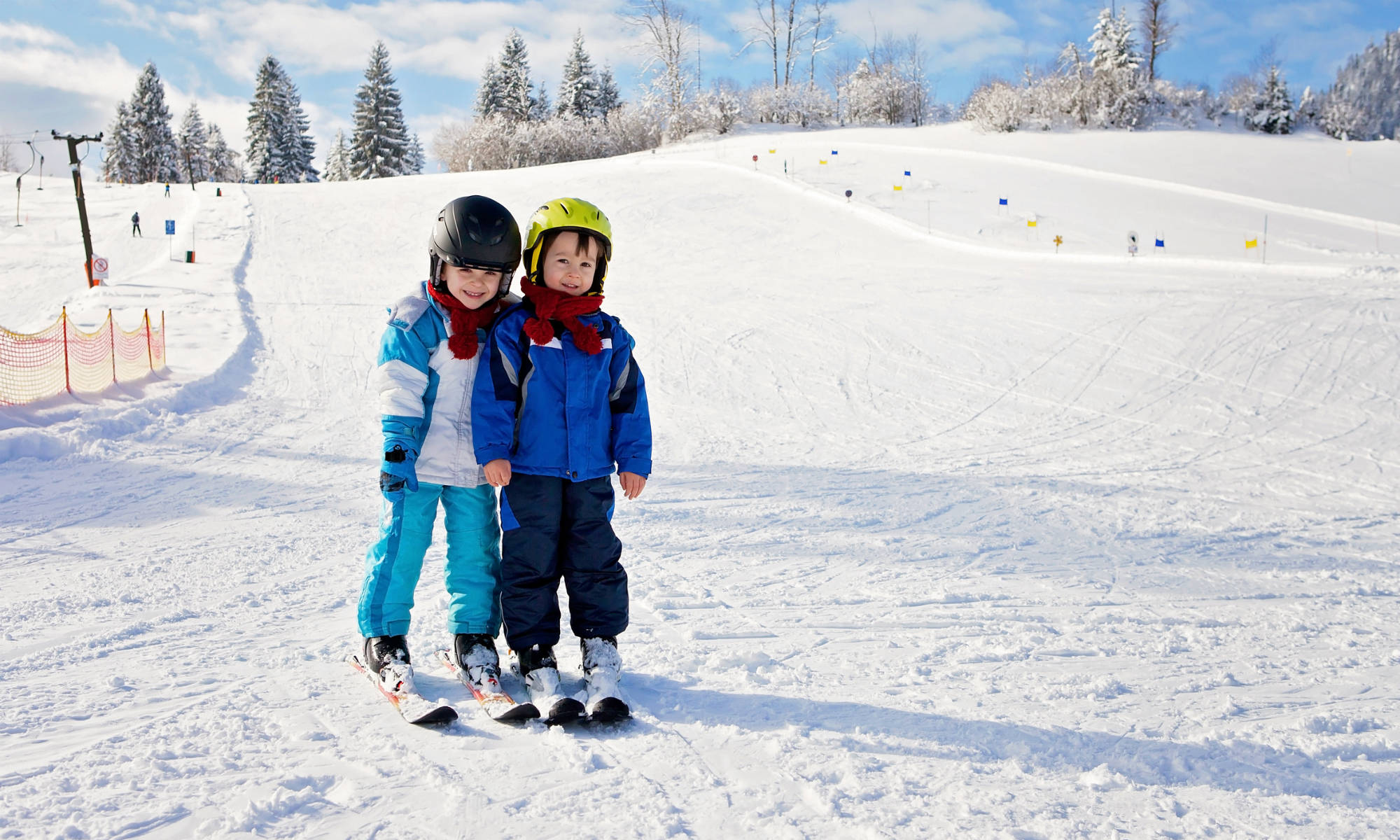 Two children carefully sliding down an easy slope.