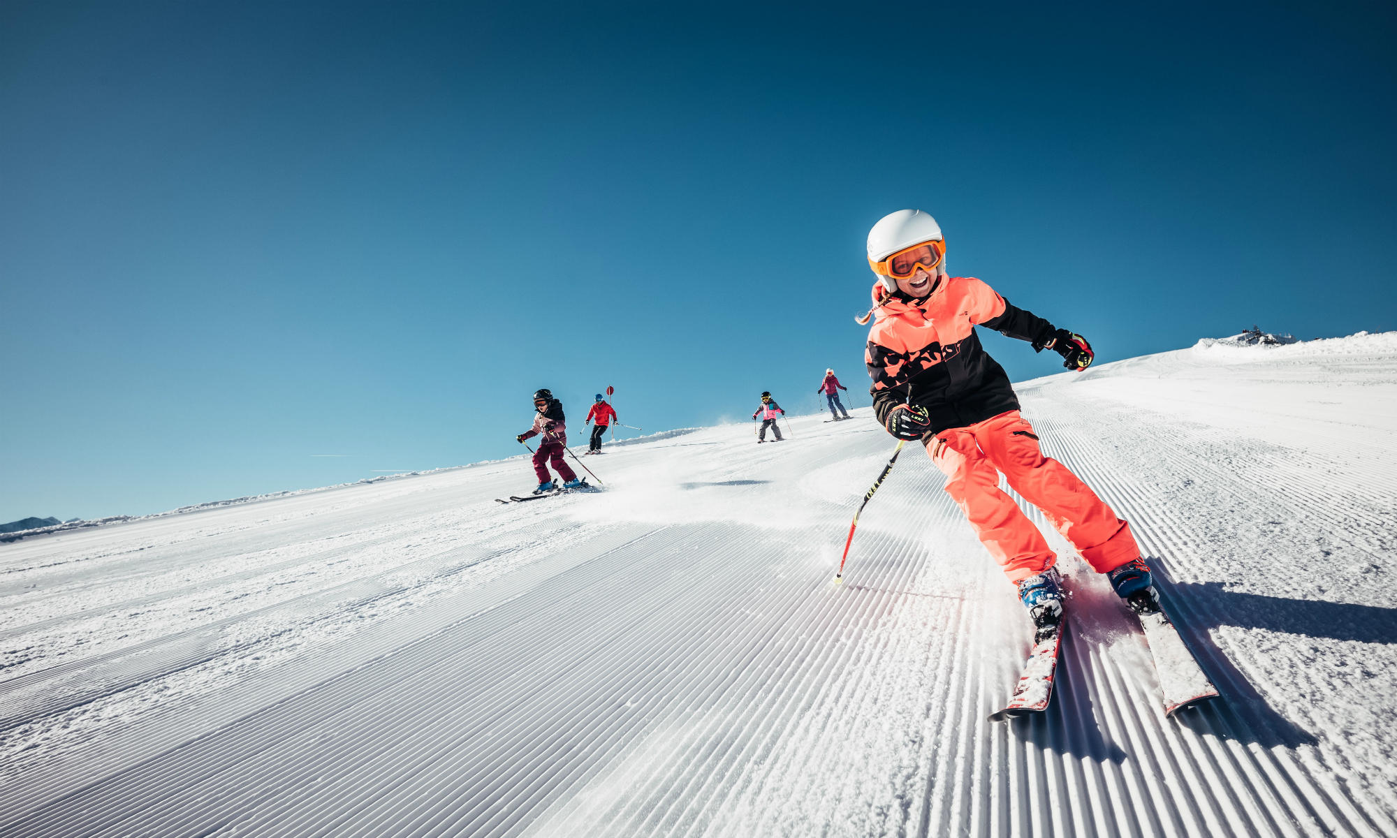 A group of children skiing on a perfectly groomed piste in the Austrian ski resort Zell am See-Kaprun.