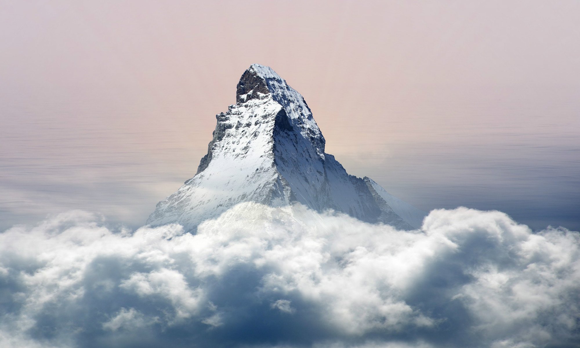 Une haute montagne se dresse dans le ciel au dessus des nuages.