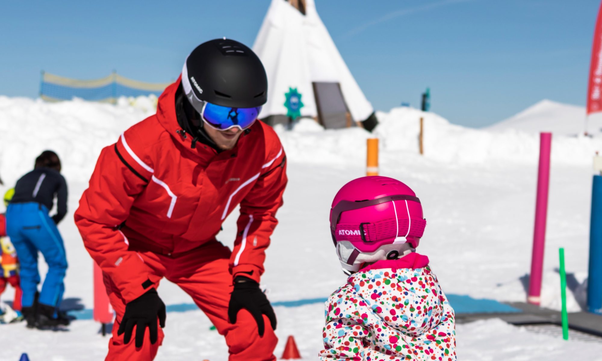 Une jeune fille débutante qui apprend à skier avec un moniteur de l'école de ski pendant les vacances d'hiver.