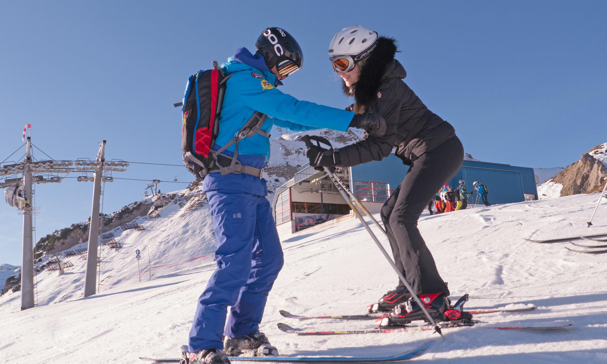 Une monitrice de ski aide une skieuse à trouver la meilleure position sur la piste.