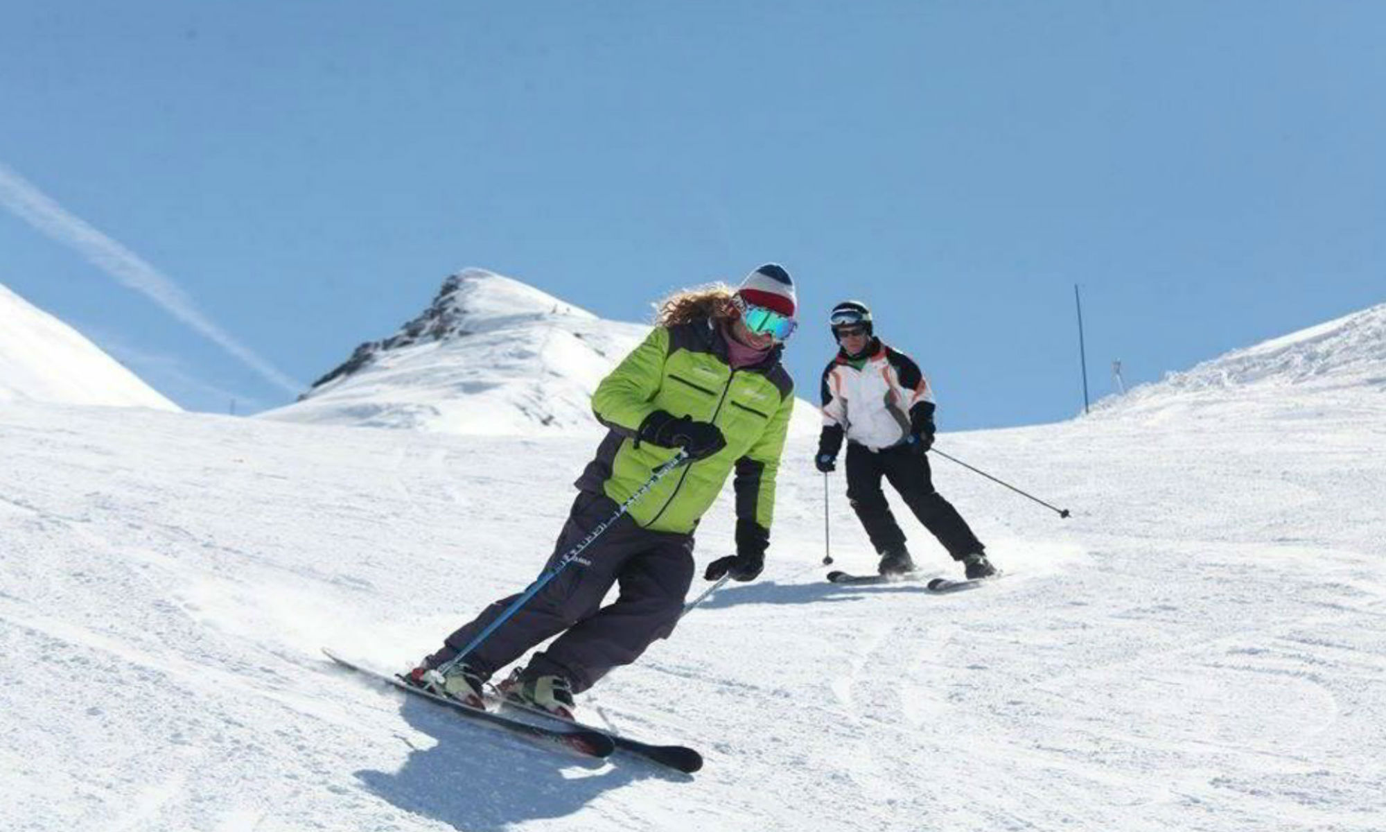Un moniteur particulier de ski et son élève sur une piste enneigée.