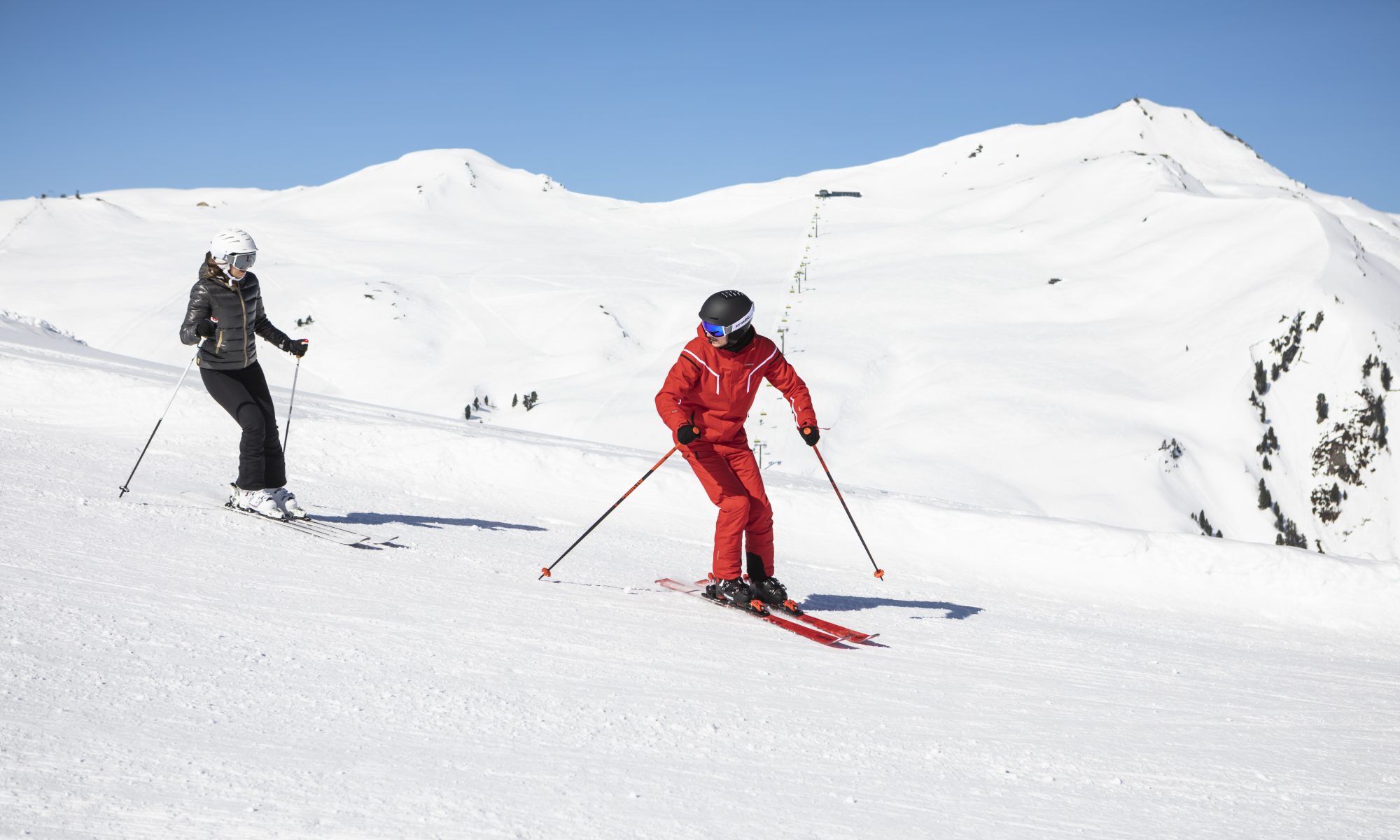 Eine erwachsene Anfängerin übt ihre ersten Skischritte mit einem erfahrenen Skilehrer.