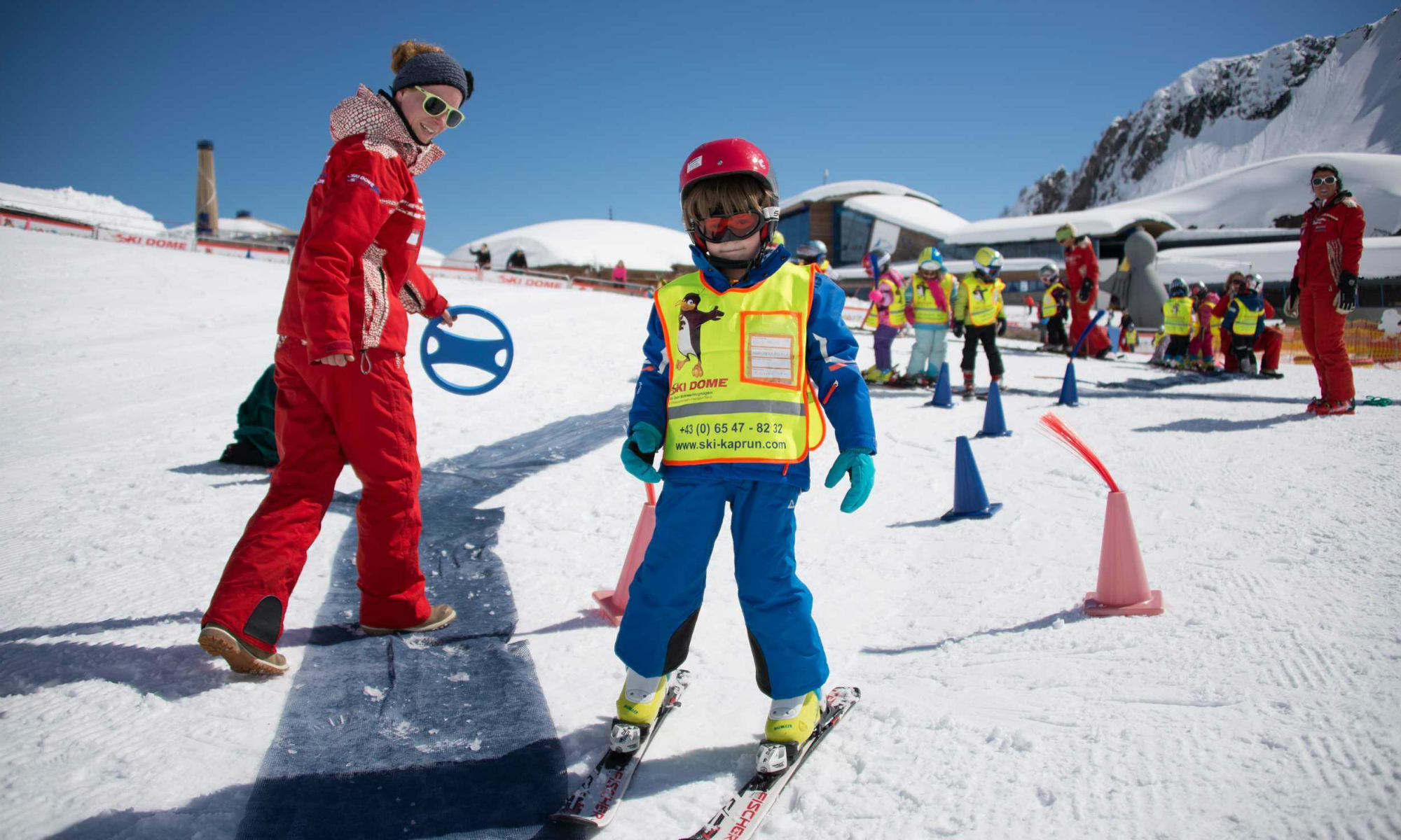 Ein Skilehrer und ein Kind üben das Skifahren im Kinderland in Kaprun.