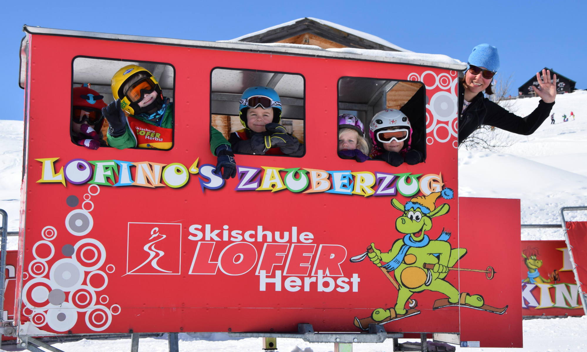 Eine Gruppe Kinder und eine Skilehrerin fahren mit dem Zauberzug zum Kinderland im Skigebiet Almenwelt Lofer. 