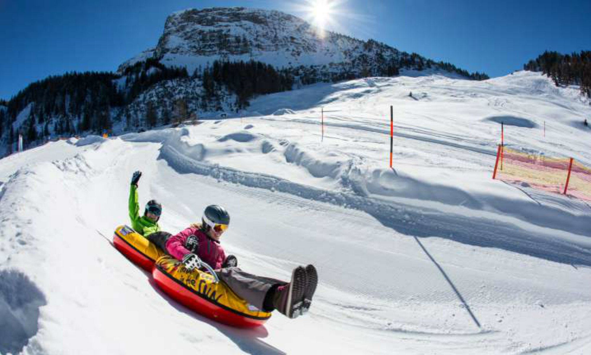 2 people snowtubing in the sunshine in the Zillertal Arena.