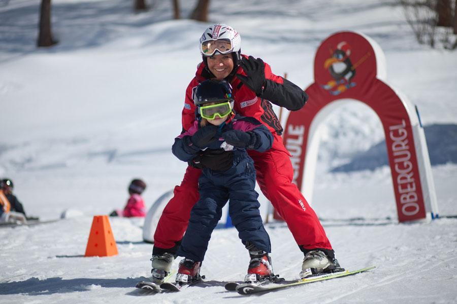 A Ski instructor and a child while practising the right skiing technique in a kids’ area.