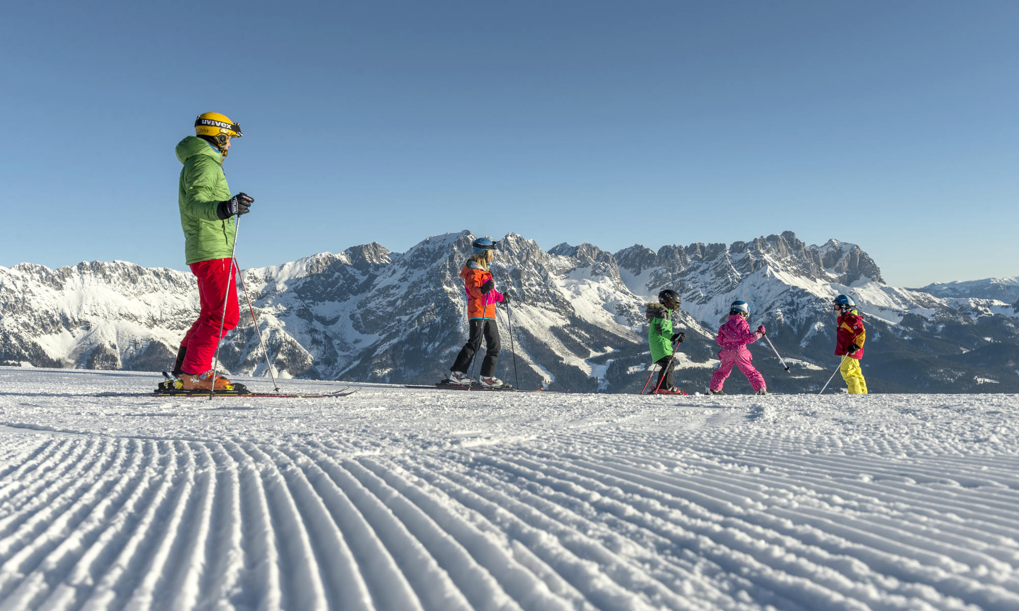 2 Erwachsene und 3 Kinder beim Skifahren in Going-Ellmau vor einer wunderschönen Bergkulisse.
