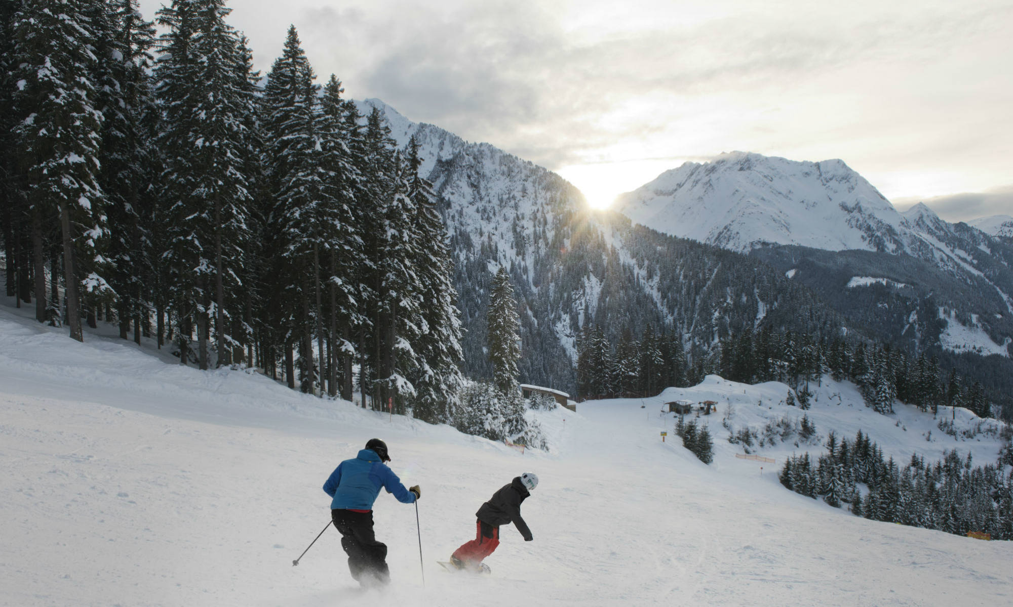 Ein Skifahrer und ein Snowboarder fahren die Piste in Mayrhofen hinunter. 