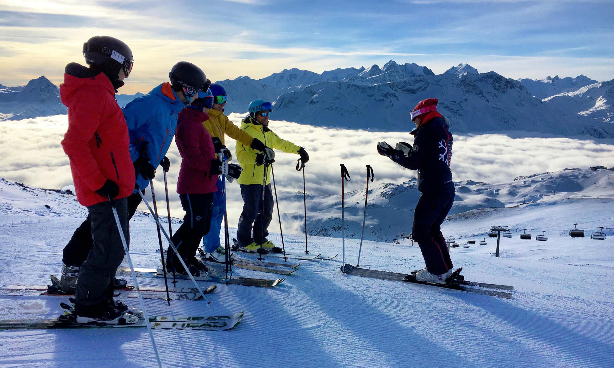 Ein Skilehrer steht mit einer Gruppe von Skifahrern am Rand der Piste.