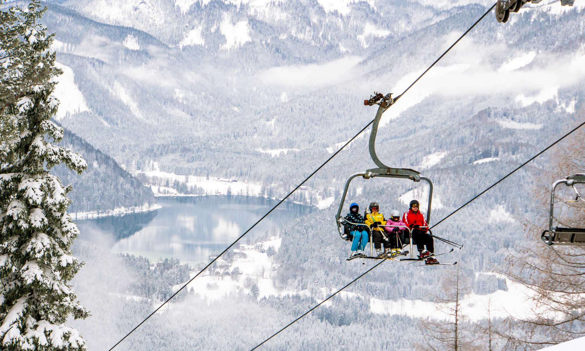  4 Skifahrer auf einem Sessellift im tief verschneiten Skigebiet Mariazell-Bürgeralpe.
