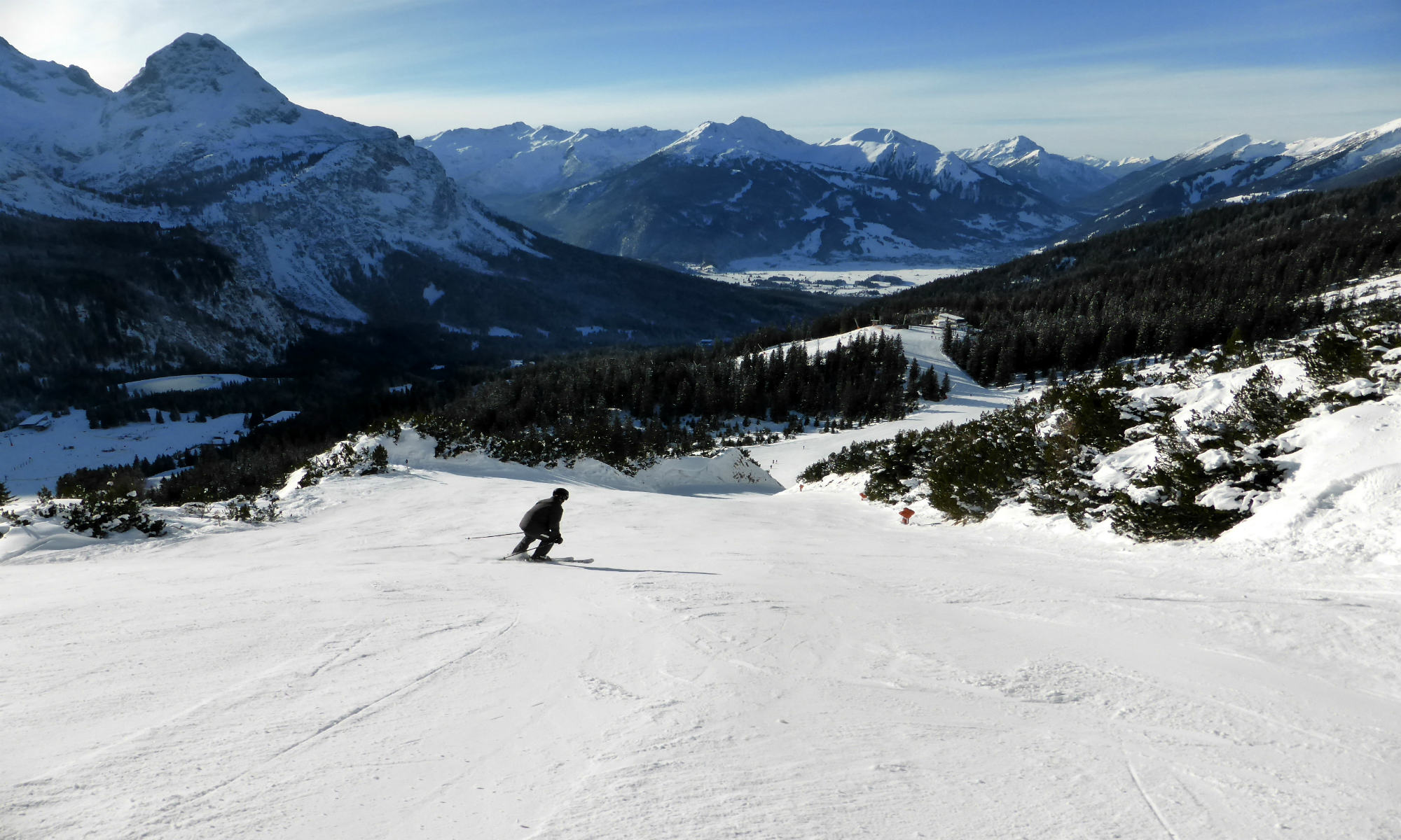 Prachtig uitzicht op het skigebied Alm, 1 persoon die naar beneden skiet.