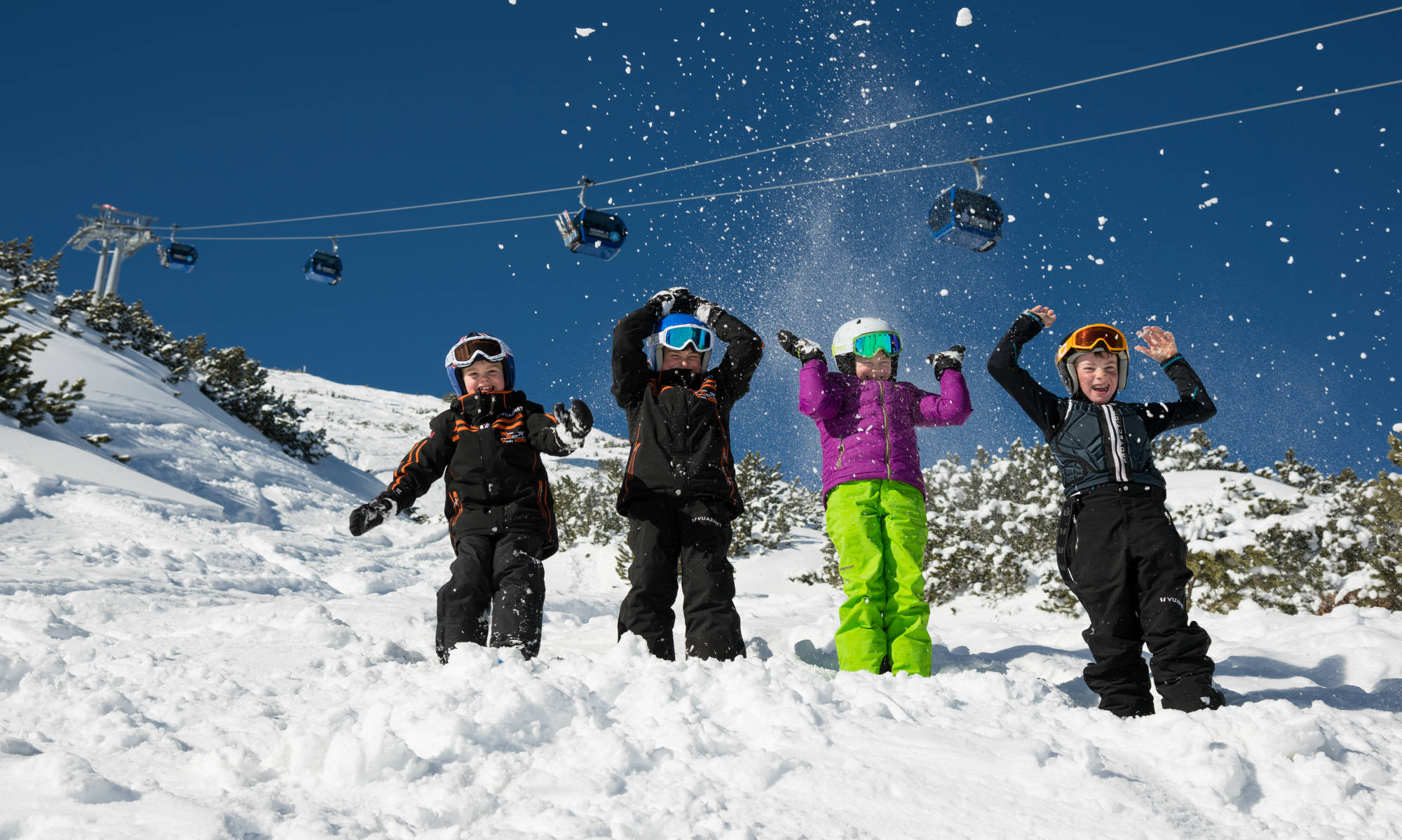 4 kinderen spelen in de sneeuw van Lermoos met de skilift op de achtergrond.