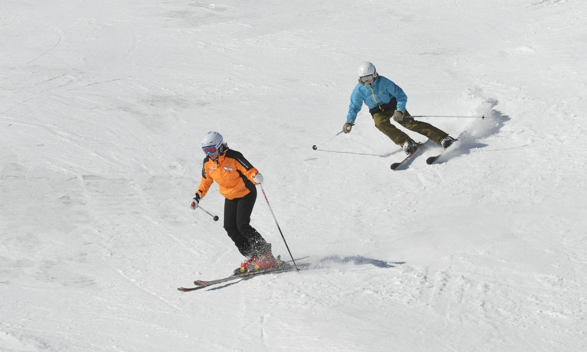 Ein Skifahrer überholt eine Skifahrerin auf der Piste.