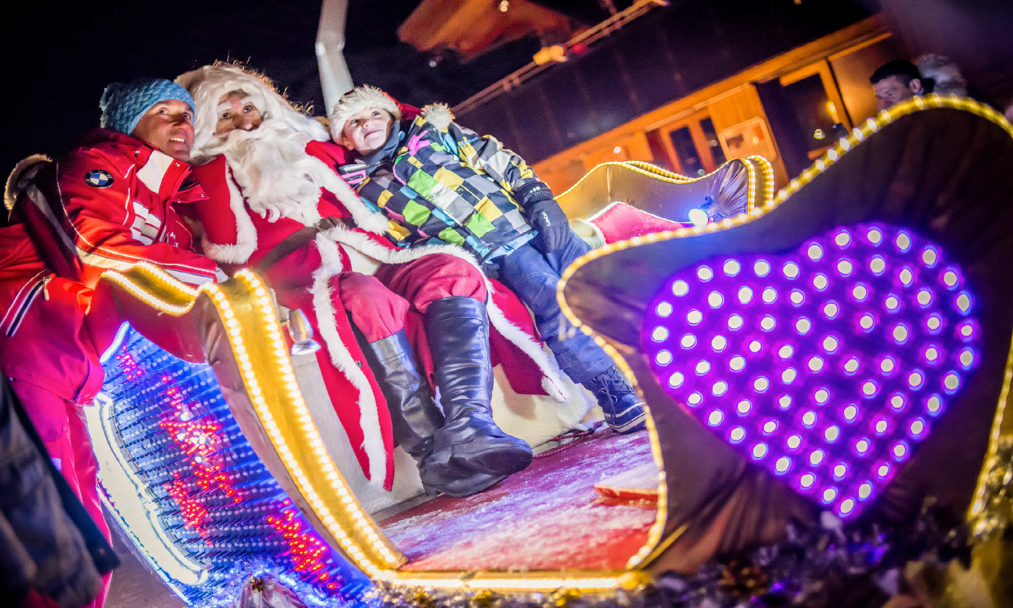 Santa Claus is posing for a picture in his sleigh together with a happy family in Tignes.