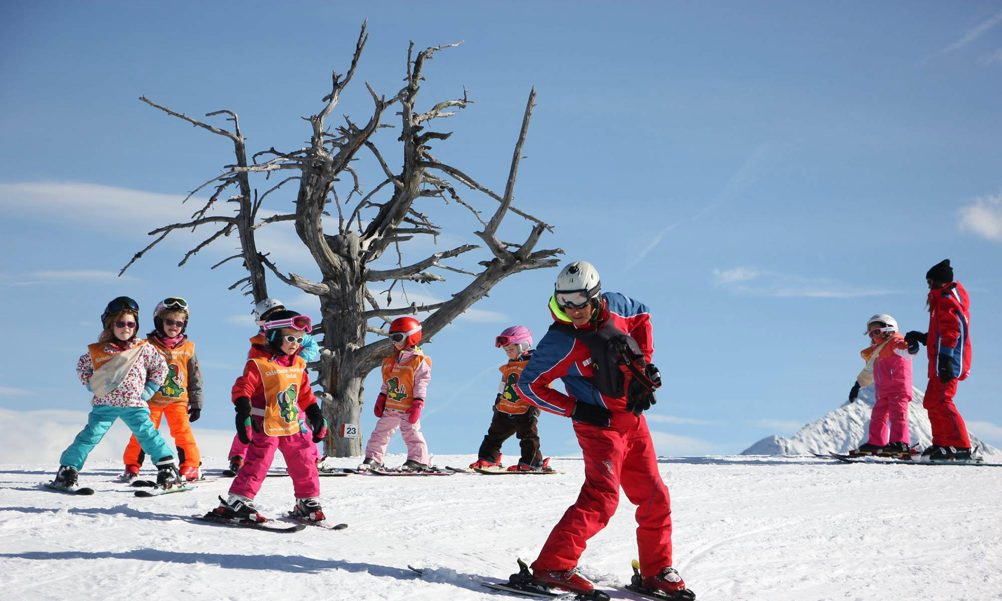 Ein Skilehrer zeigt einer Gruppe Kinder die richtige Technik auf einer Piste im Skigebiet Mayrhofen.