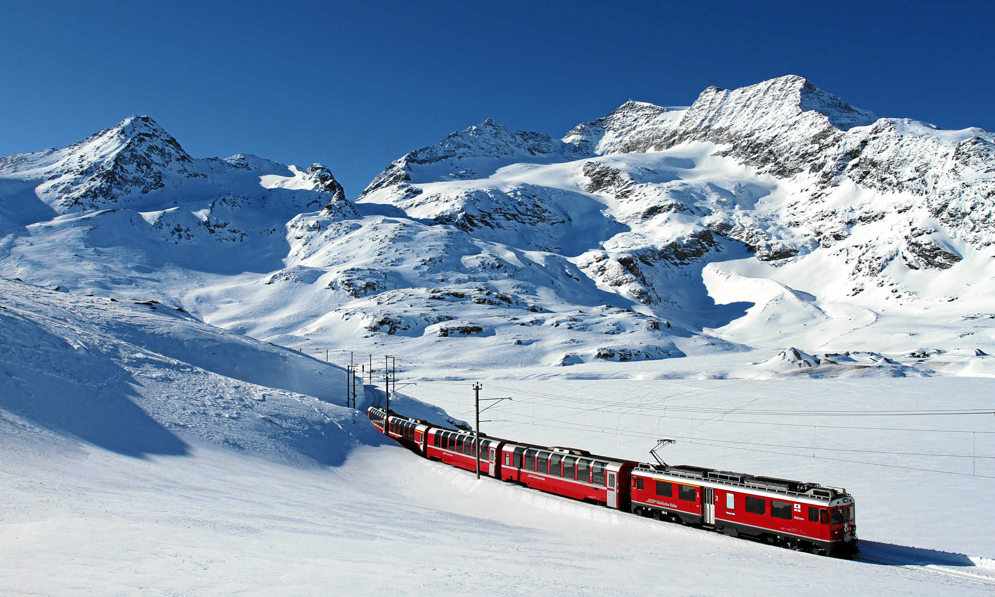 Der Bernina Express fährt entlang des Lago Bianco in den Schweizer Alpen.