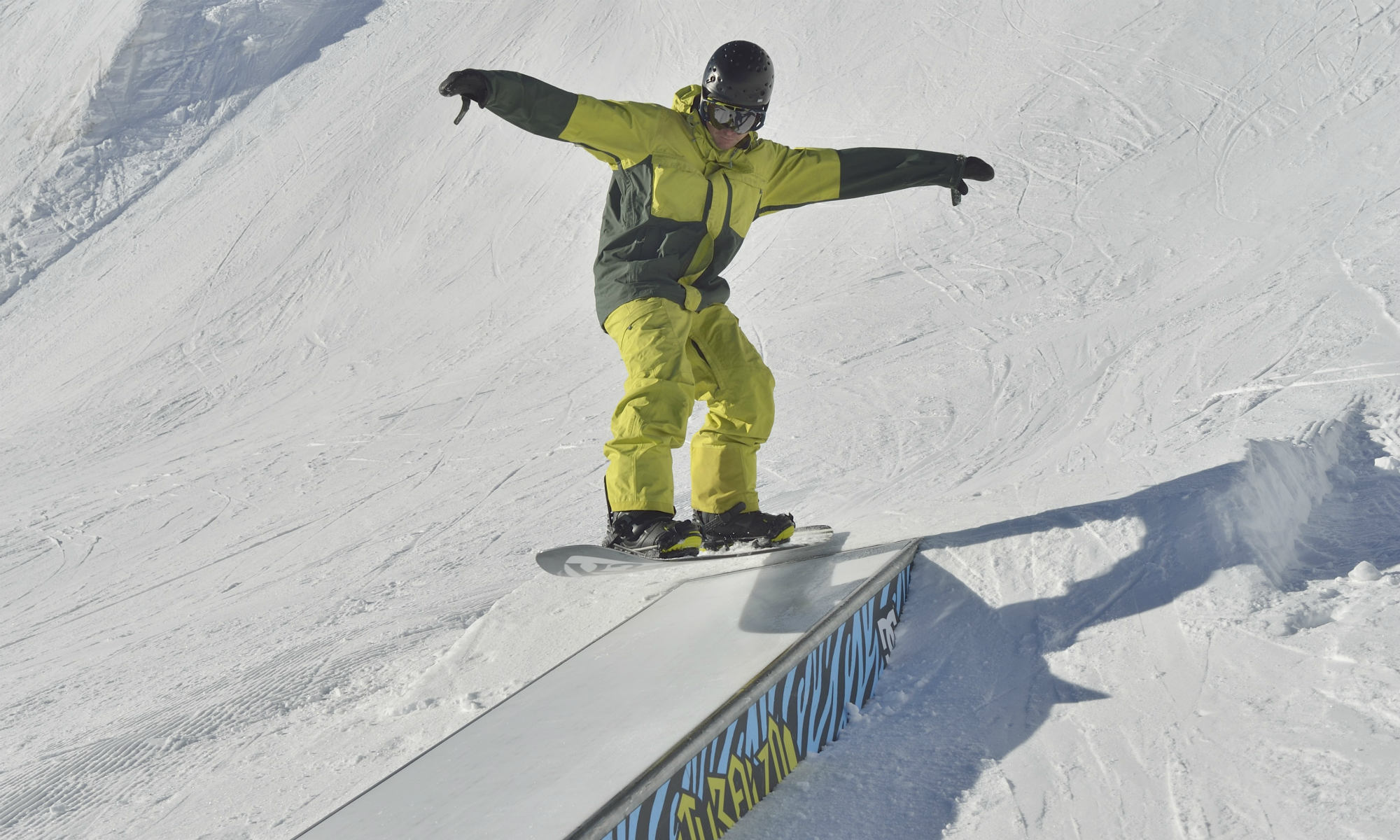 Ein Snowboarder fährt über eine Box in einem Funpark in Nendaz.