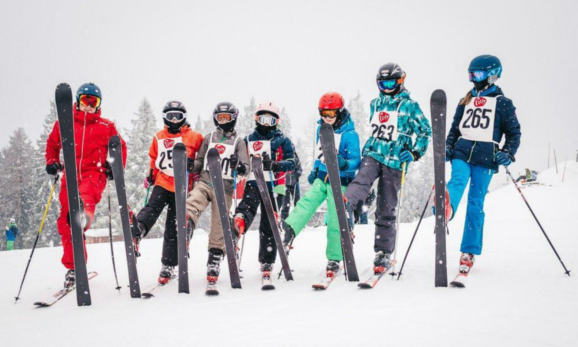 Ein Skilehrer und 6 Kinder posieren mit aufgestellten Skiern auf einer Piste der Mariazeller Bürgeralpe. 