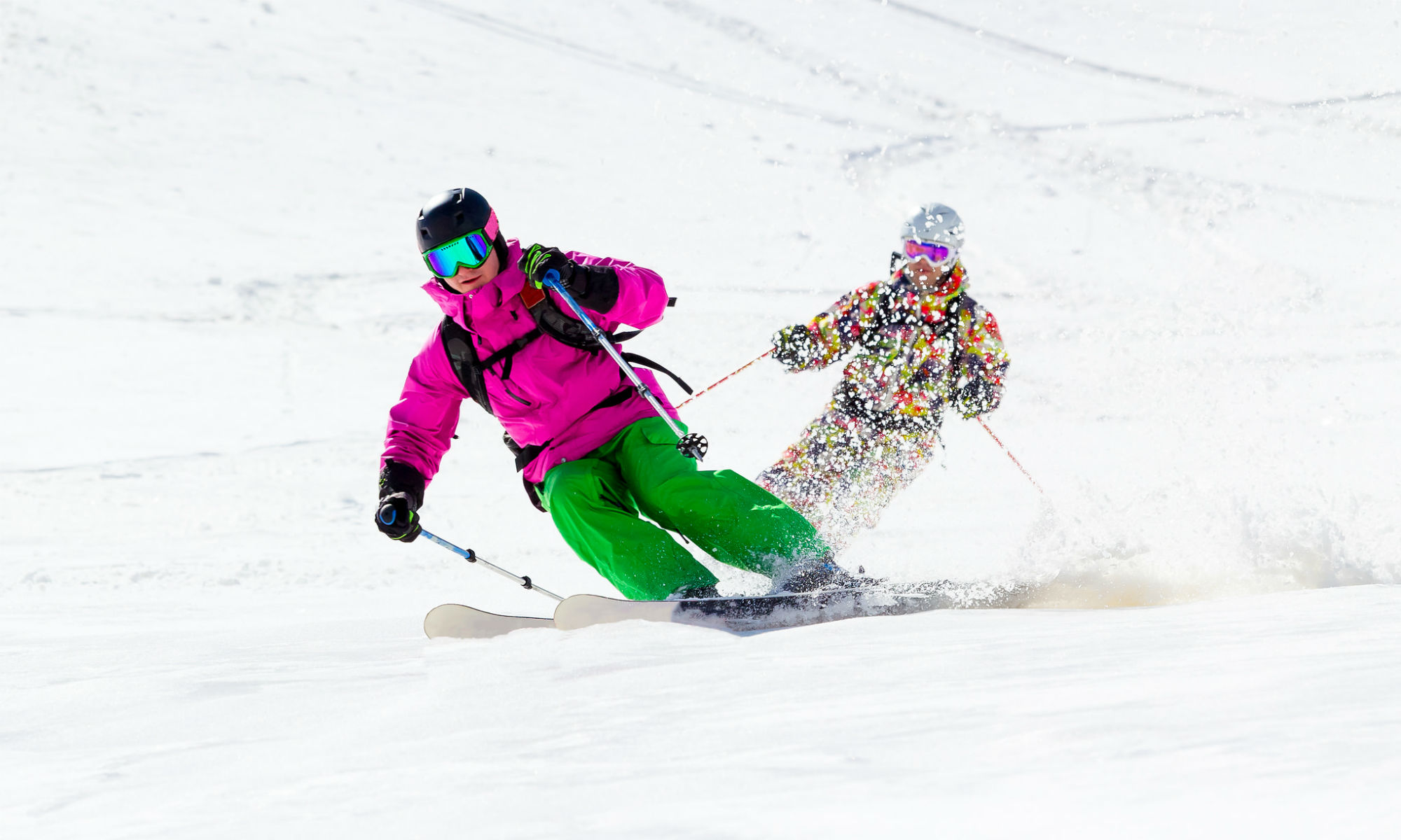 Two skiers skiing in powder snow.