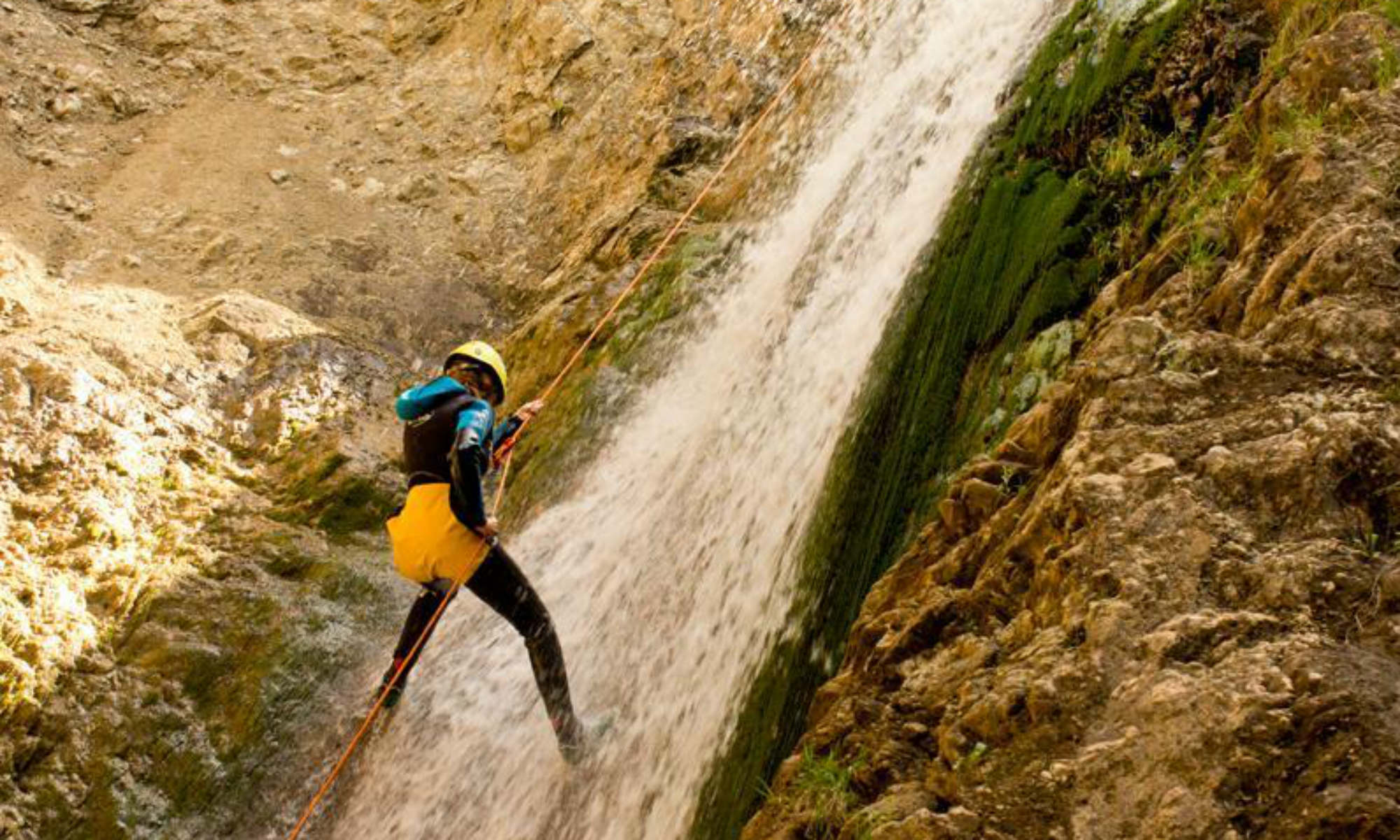 Ein Teilnehmer seilt sich beim Canyoning in Spanien an einem Wasserfall ab.