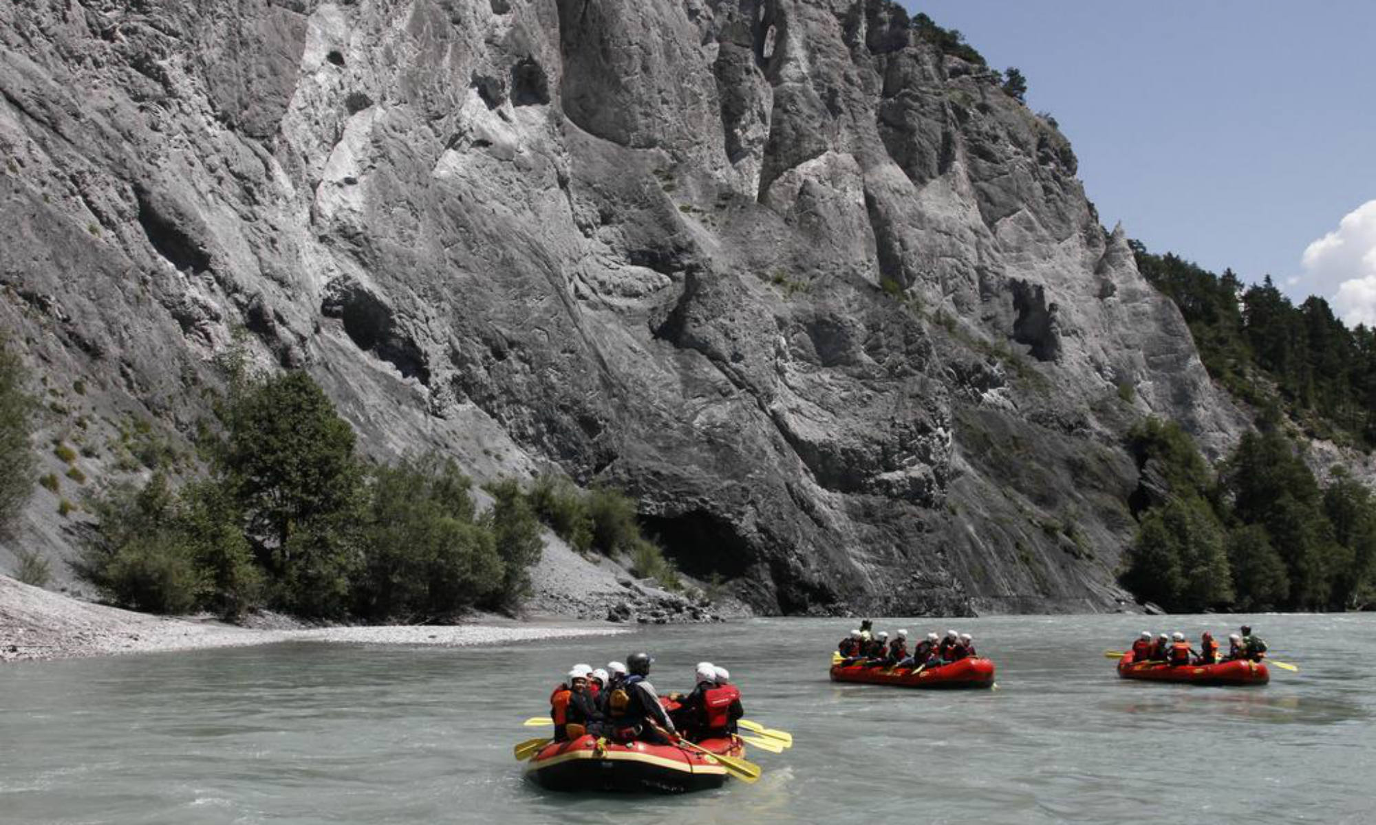 Mehrere Gruppen beim Rafting am Vorderrhein in der Schweiz.