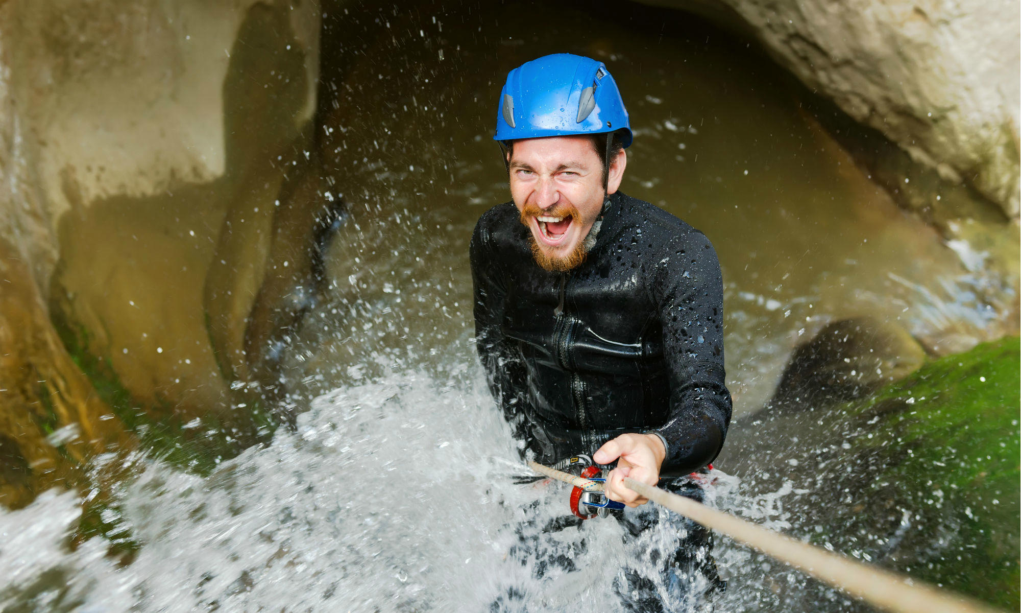 Ein junger Mann beim Abseilen in einer Schlucht bei Interlaken in der Schweiz.