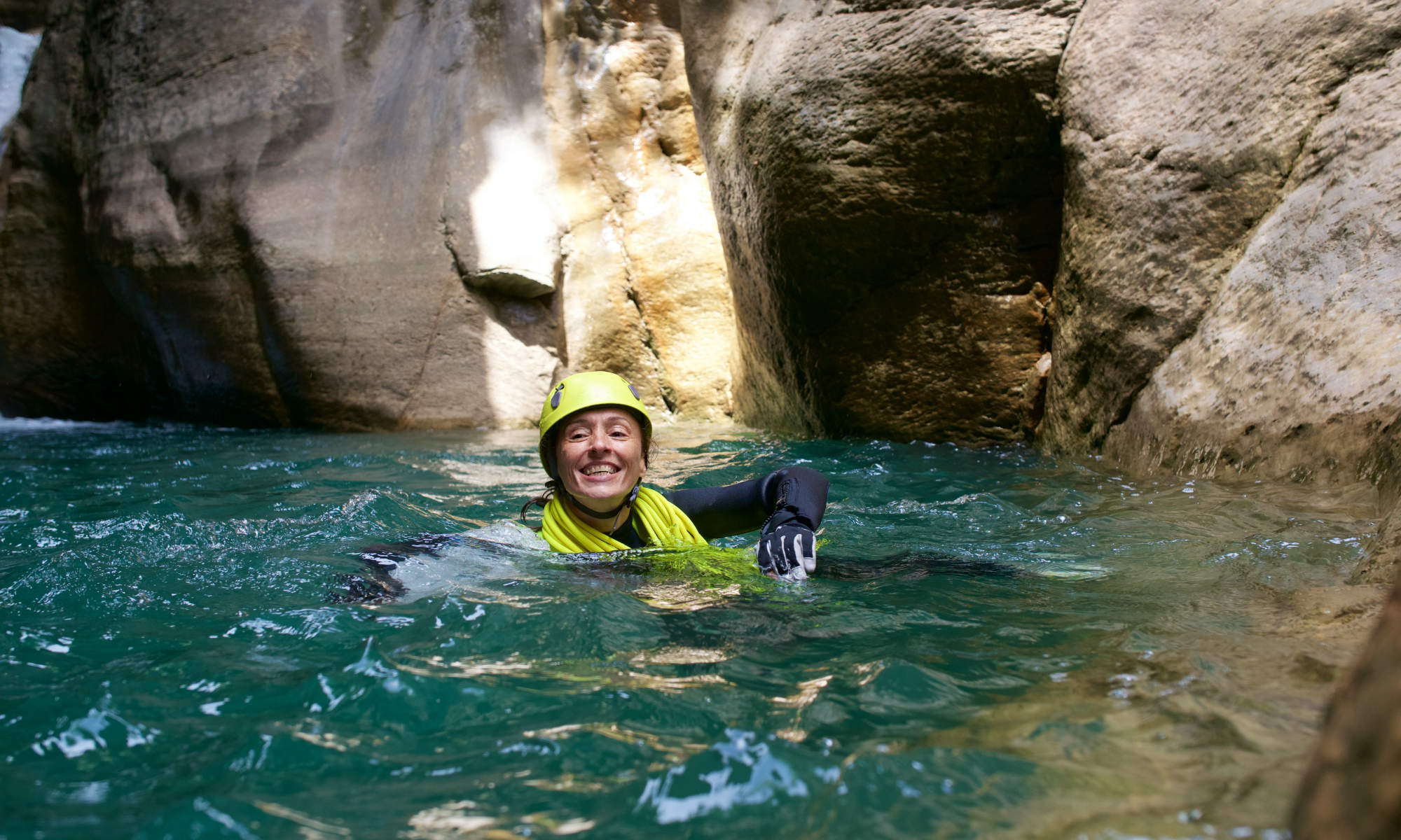 Eine Teilnehmerin einer Canyoning Tour schwimmt in einem Wasserbecken.