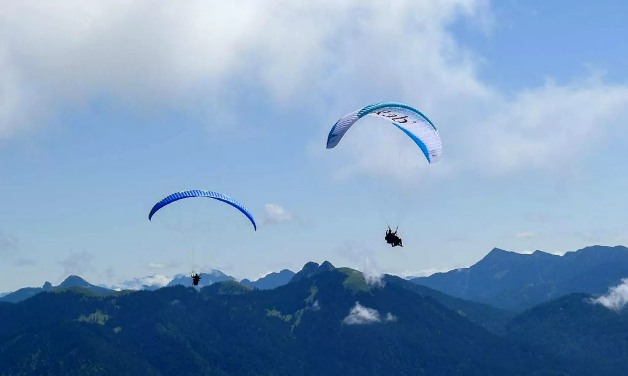 Le panorama montagneux des Alpes bavaroises avec 2 parapentes au premier plan.