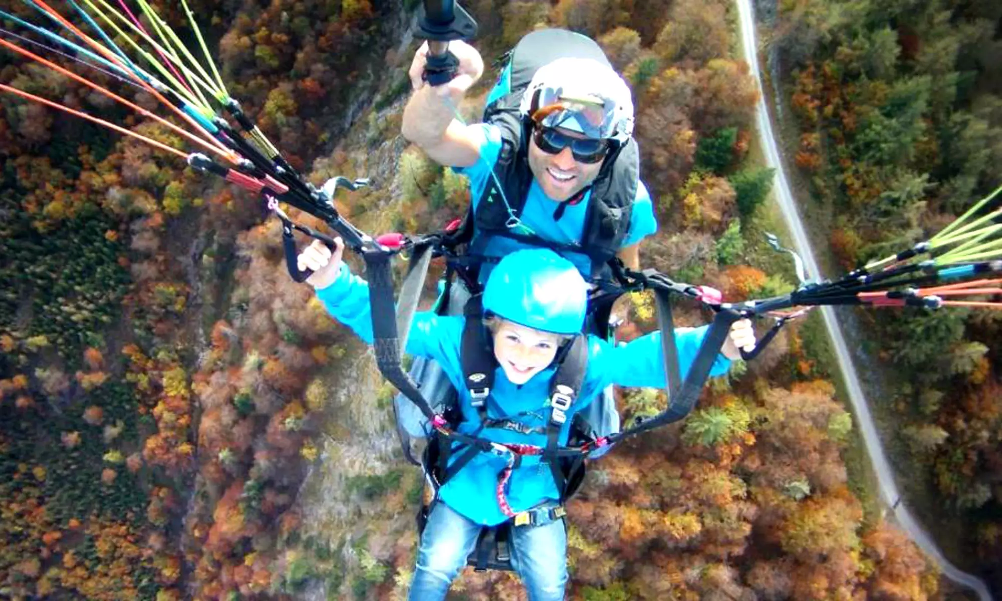 Un pilote de parapente avec un enfant au-dessus des forêts de Kössen en Autriche.