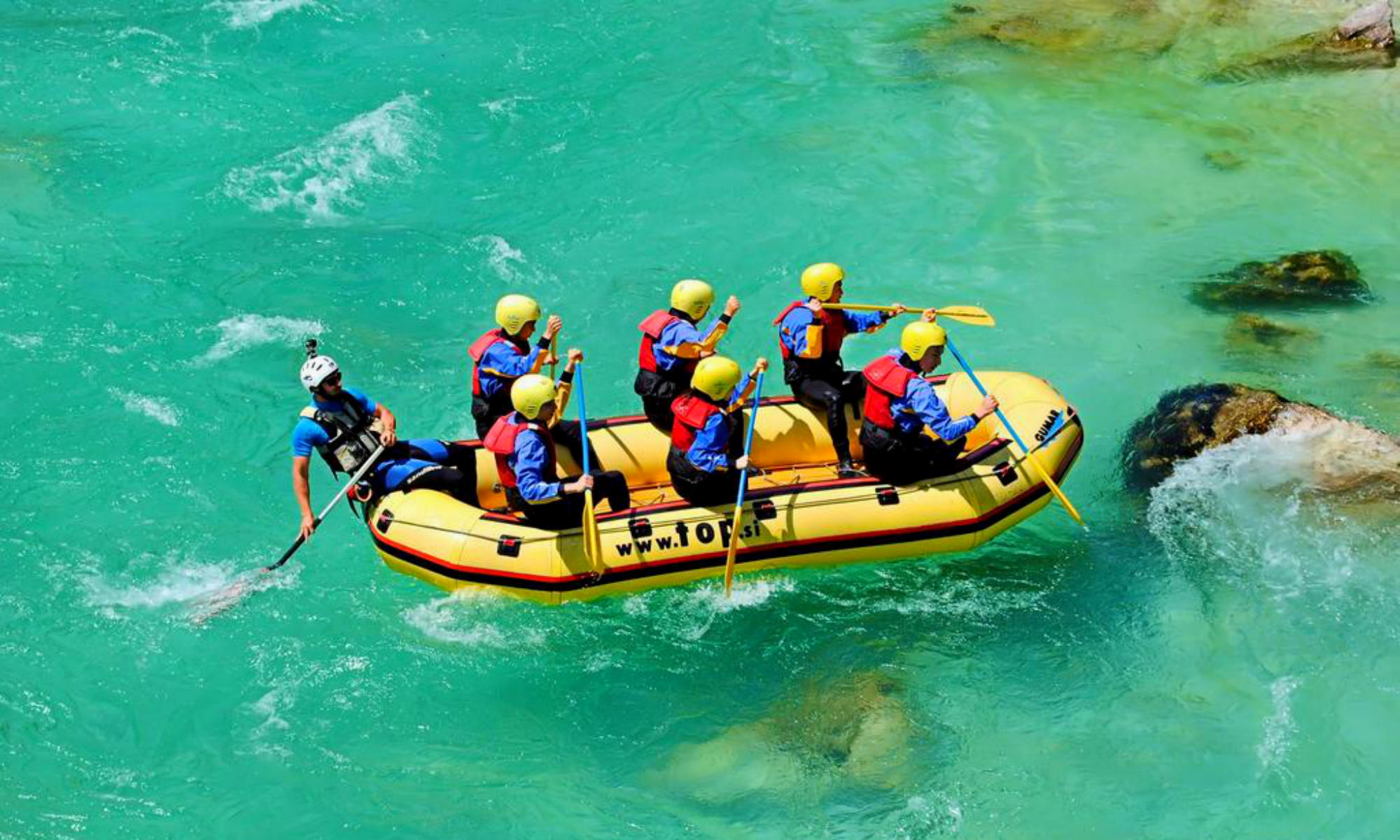 Un gruppo sta facendo rafting sull’Isonzo. La colorazione dell’acqua è di un verde intenso.