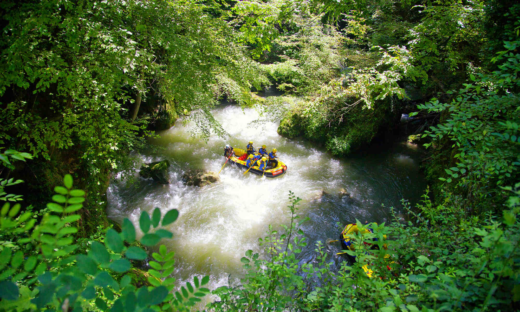 Due barche immerse nel verde scendono il fiume durante il rafting in Italia.