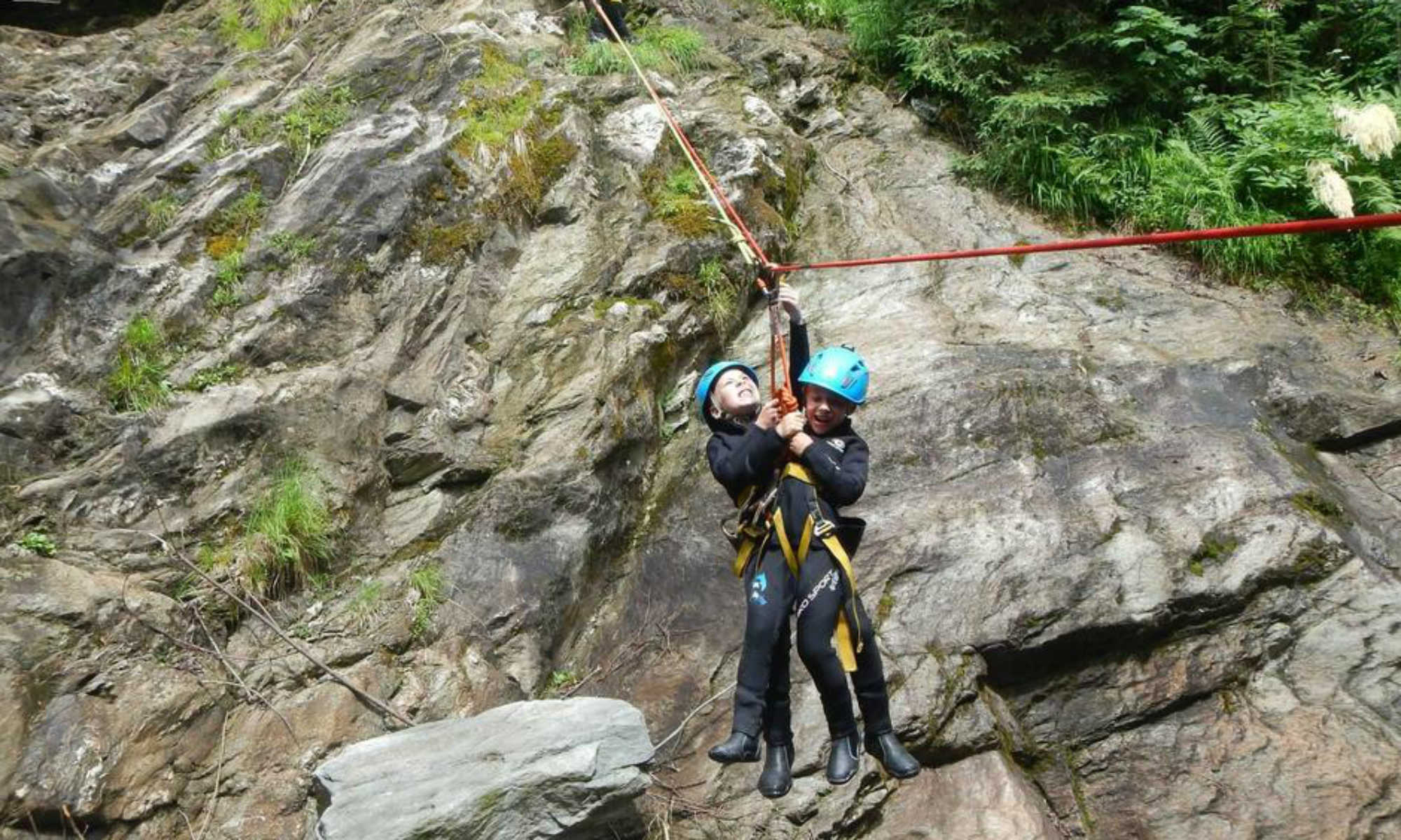 2 Kinder gleiten mit dem Flying Fox durch eine Schlucht beim Canyoning bei Taxenbach.