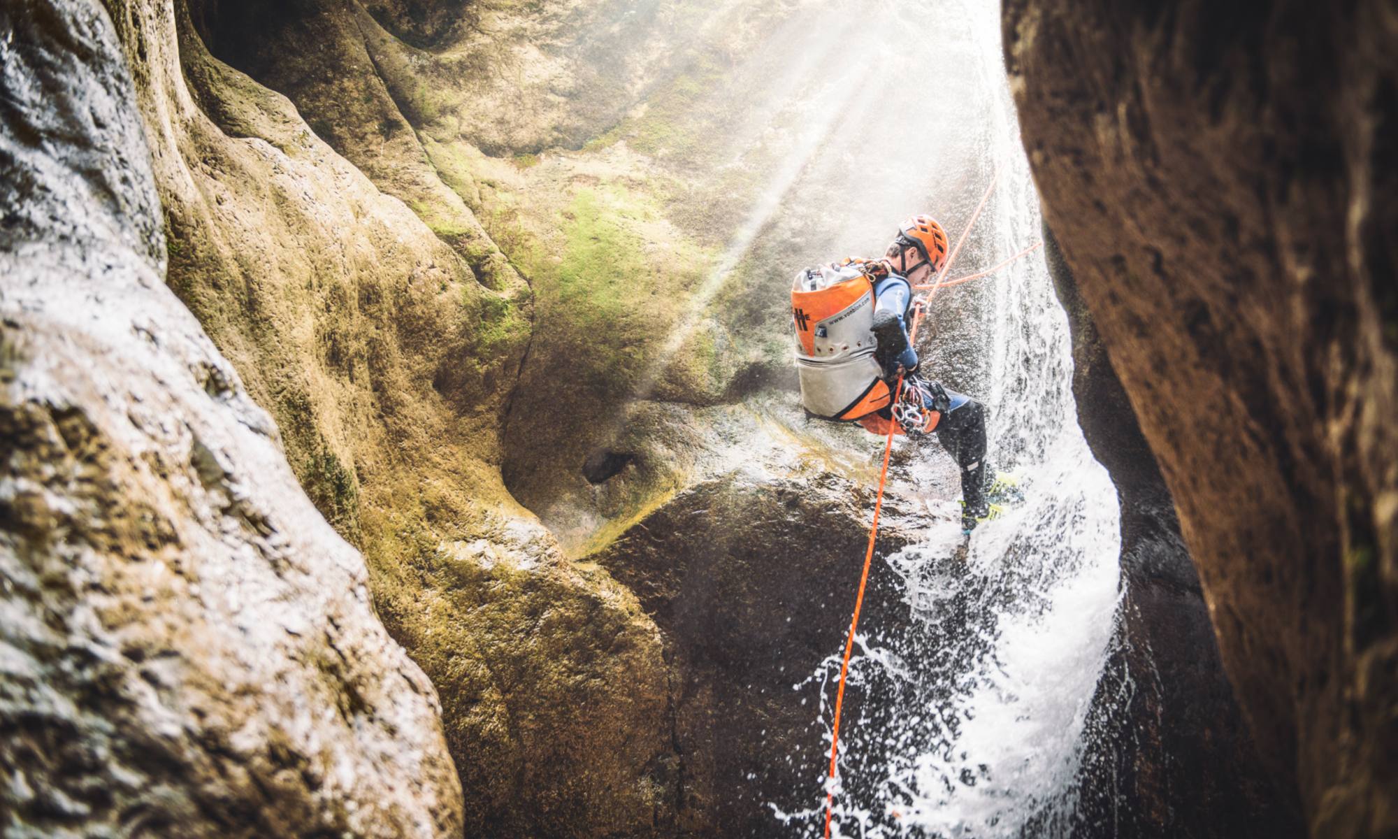 Ein Mann seilt sich beim Canyoning in der Steiermark in Palfau an einem kleinen Wasserfall ab.
