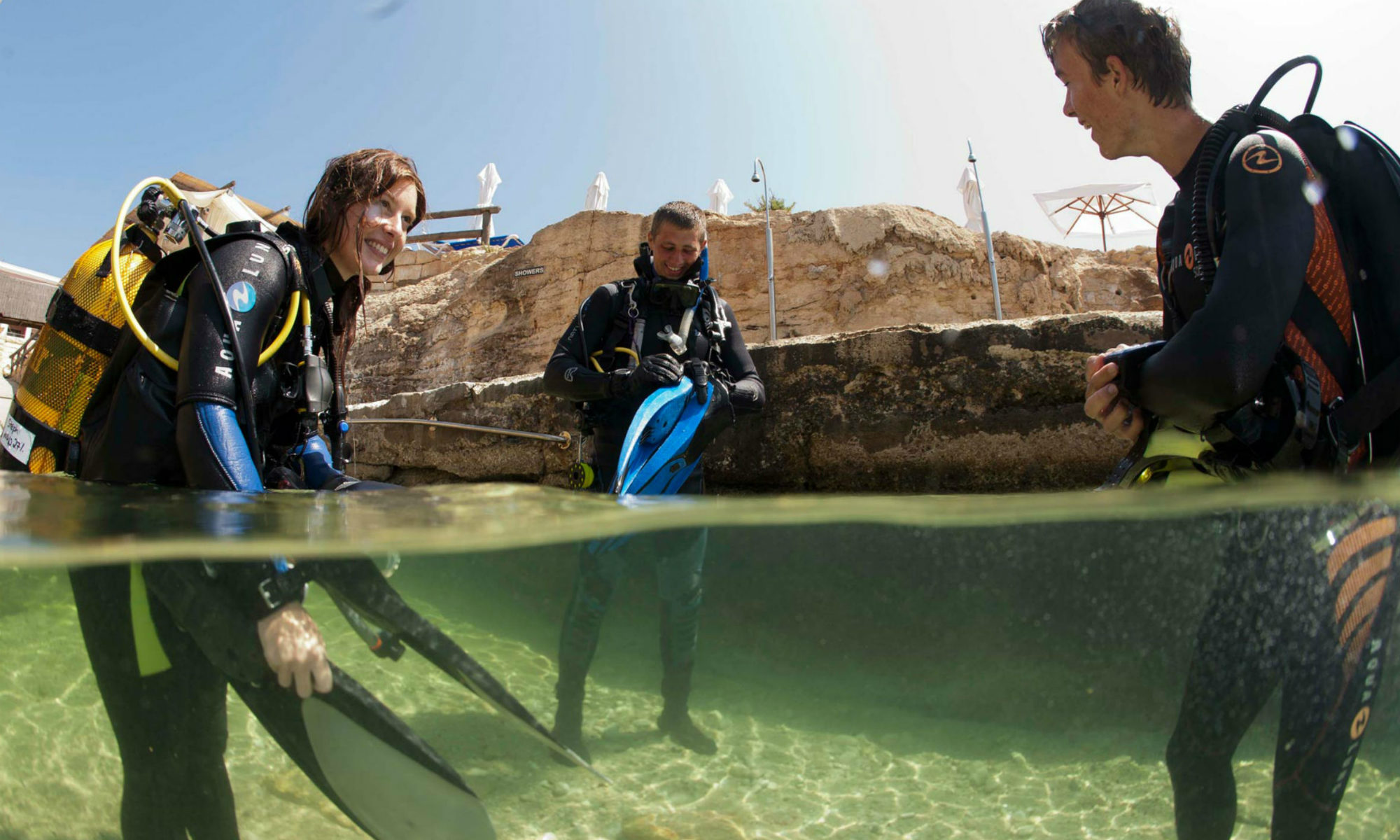 A group of divers gearing up in shallow water, preparing to go scuba diving in Malta.