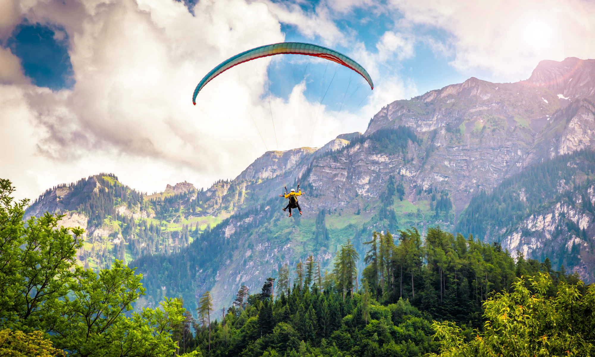 Ein Paraglider gleitet vor der Bergkulisse in Interlaken durch die Lüfte.