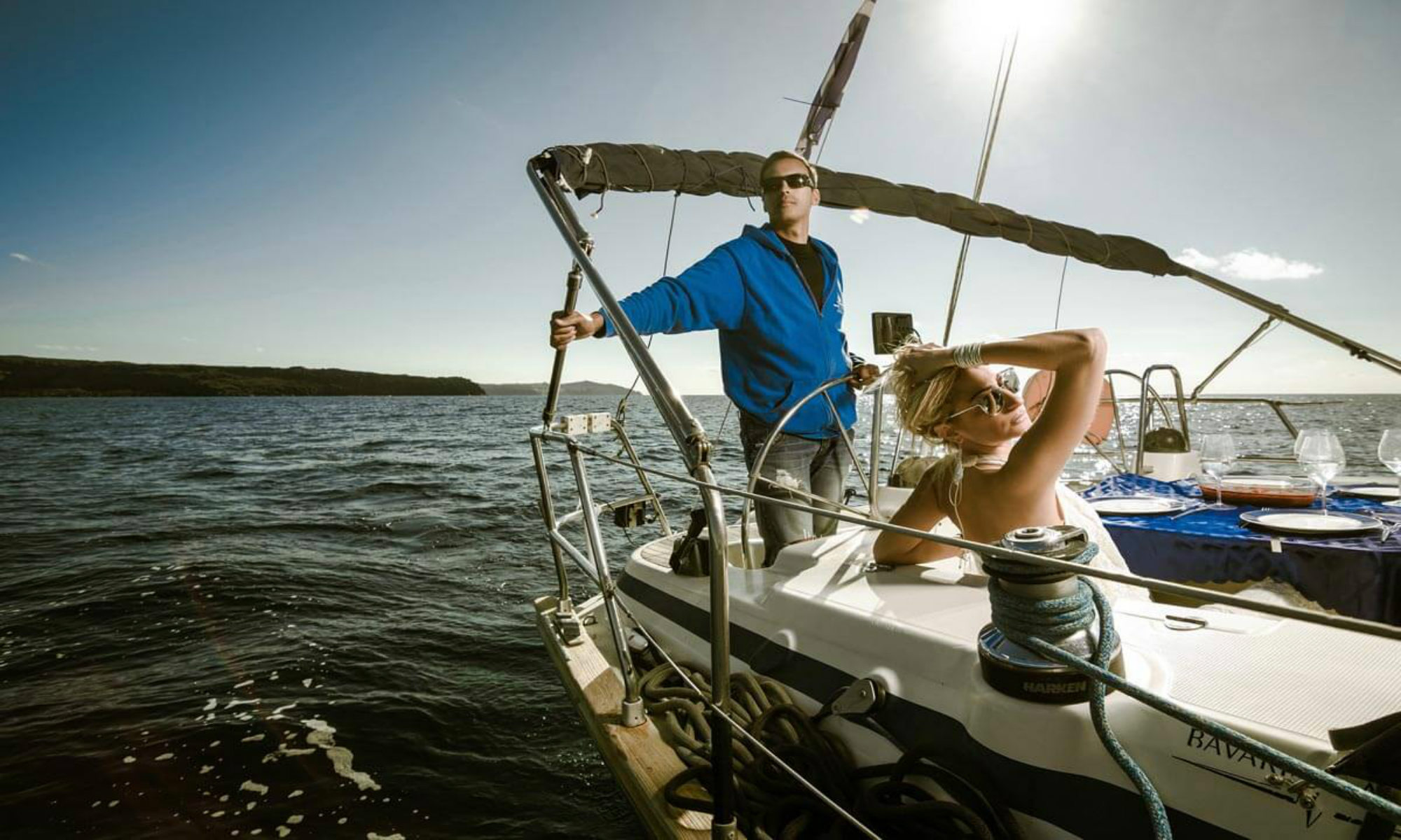 The captain and his female guest are enjoying a boat tour around the island of Santorini.