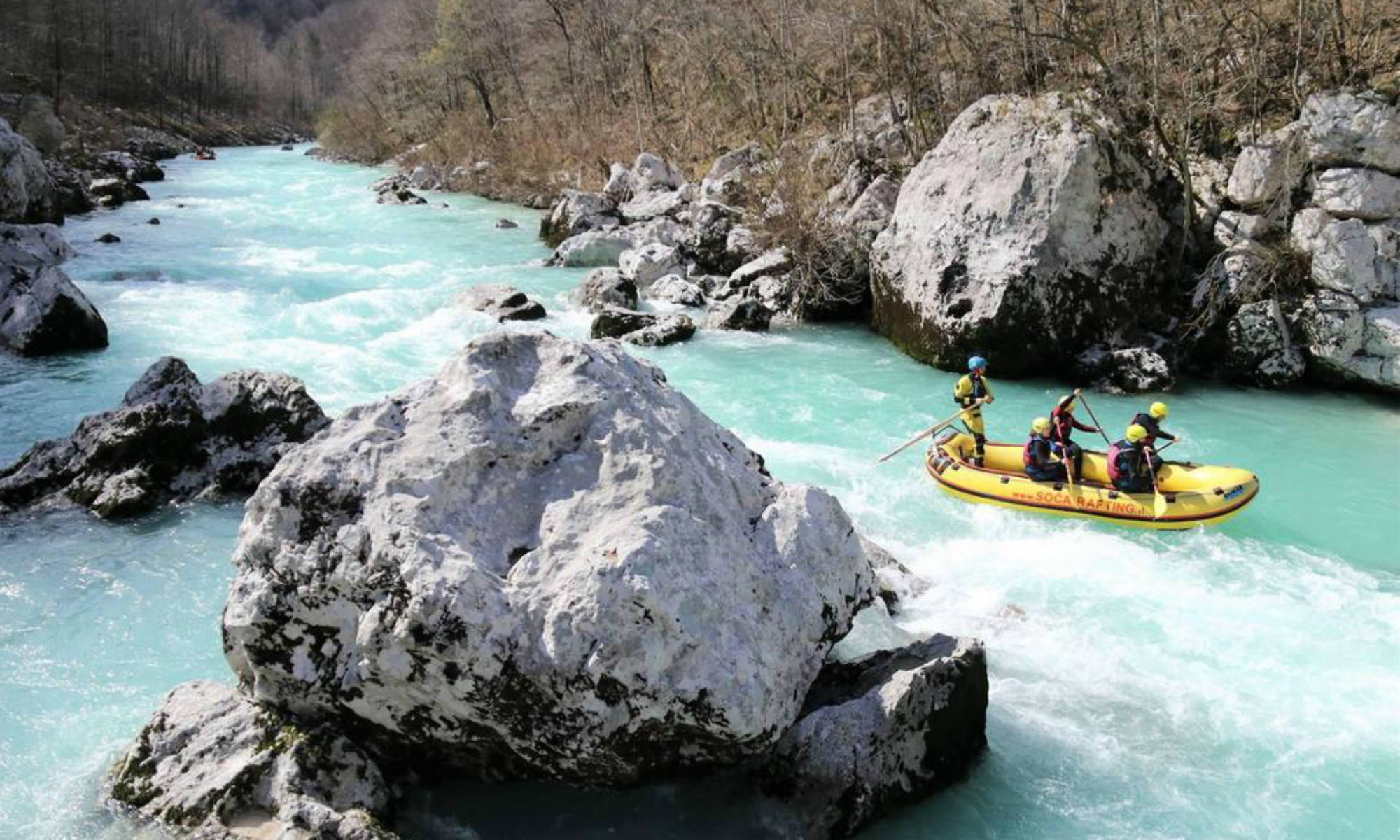 A group of people dodging the rocks in the water while rafting on the Soča River.