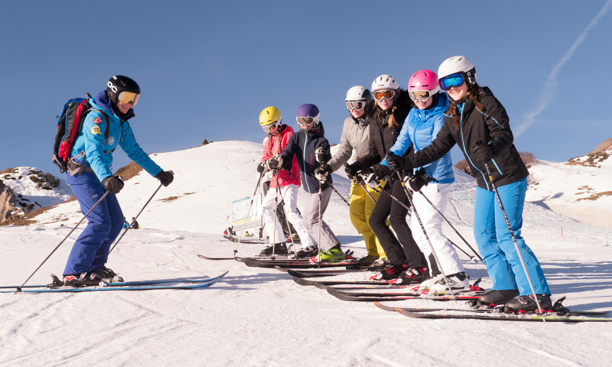 Een groep tieners op een zonnige piste tijdens het skiën.