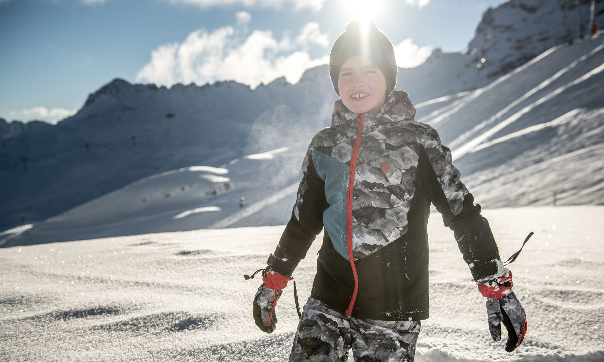 Een kleine jongen in een camo ski outfit.