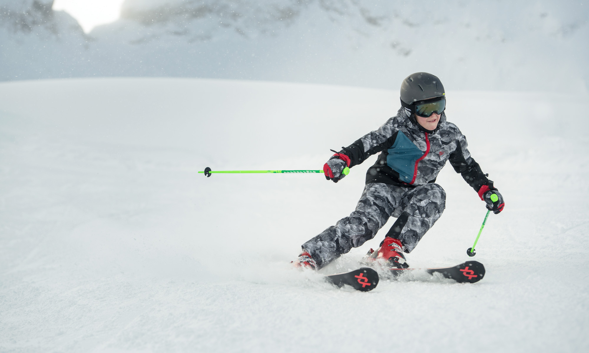 Een jongen in een camouflage outfit skiet van de piste.