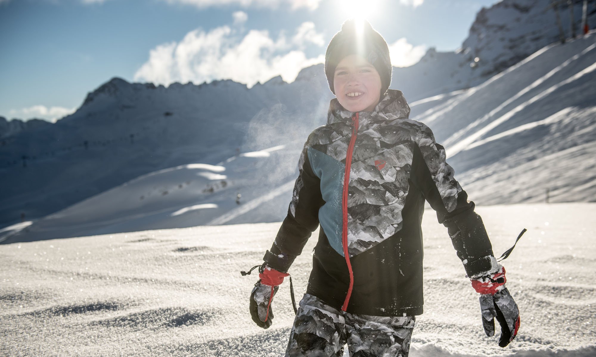 Ein Junge im grauen Ski Outfit.