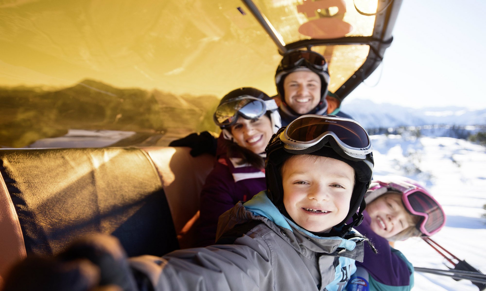 Een jongetje maakt een selfie in de skilift met zijn ouders en zus.